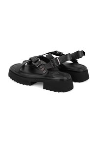 Schwarze Plattform-Sandalen mit mehreren Riemen, aus einem glatten, lederähnlichen Material, mit Schnallen und einer strukturierten, genoppten Sohle.