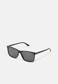 Black plastic sunglasses with square frames, dark lenses, thin arms, and silver accents on the tips. Polaroid branding visible on the arm.