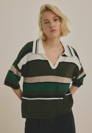 Knit pullover with a V-neck, featuring contrasting stripes in green, beige, black, and white; short sleeves and relaxed fit.