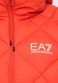 Red puffer jacket with a quilted pattern, featuring a central zipper, black zipper pulls, and a white EA7 Emporio Armani logo.
