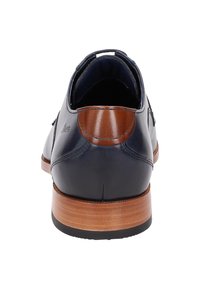 Chaussure en cuir marine avec une finition lisse et un accent marron sur le talon. Présente un talon empilé en bois et un design à bout rond.