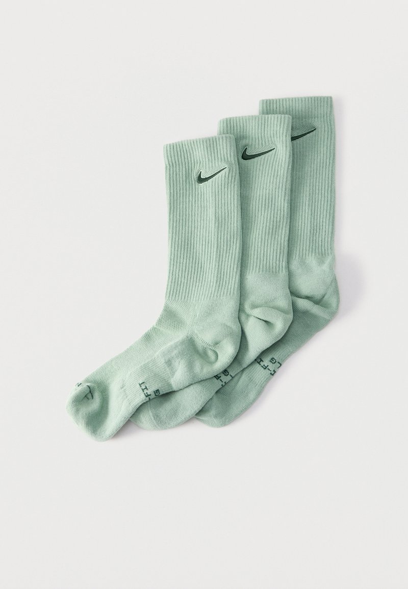 Τρία ζευγάρια ανοιχτό πράσινες κάλτσες Nike crew με μαύρα λογότυπα, τοποθετημένες επικαλυπτόμενες σε λευκό φόντο.