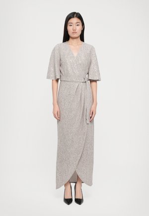 Lange, lichte wikkeljurk in lichtbeige met een subtiele glans, voorzien van korte mouwen, een strik taille en een asymmetrische zoom.