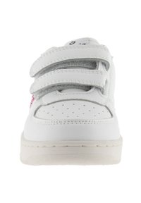 Sneaker blanc avec un bout perforé, deux bandes Velcro et un détail rose sur le côté, présenté en vue de face.