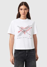 Λευκό βαμβακερό t-shirt με κοντό σχέδιο. Διαθέτει κόκκινη καρδιά με βέλος, περιβαλλόμενη από κείμενο και σχέδιο που μοιάζει με αίμα.