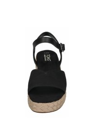 Zwarte TOMS sandaal met enkelbandje, gesp sluiting, geweven beige platformzool en open teen ontwerp.