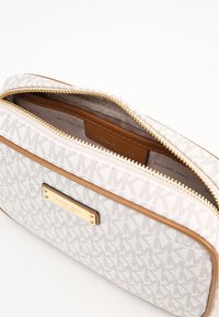 Borsa sintetica bianca con motivo a monogramma MK, rifiniture in pelle marrone, accessori in oro, chiusura con zip e interno beige.