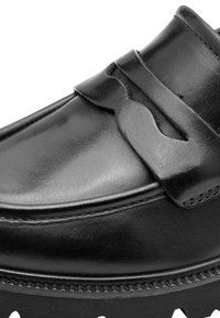 Κοντινή λήψη ενός μαύρου δερμάτινου loafer με διακοσμητικό λουράκι και λεπτομερείς ραφές κατά μήκος της άκρης της σόλας.