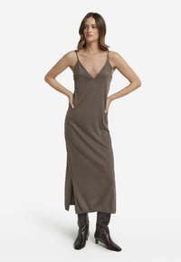 Lång, brun, ärmlös klänning i tankstil med djup V-ringning och sidoklipp. Tillverkad av mjukt tyg, den har justerbara remmar och en avslappnad passform.