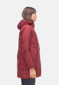Giacca a vento rossa con cappuccio, caratterizzata da una vestibilità dritta, tasche con zip e una trama di tessuto liscia e resistente.