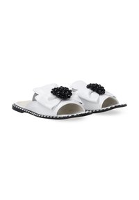 Witte open teen slide sandalen met een grote zwarte bloemenversiering en zilveraccenten langs de zwarte zool. Gezellige leren afwerking.