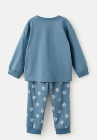 Blå bomullspyjamas i set om att inkludera en långärmad topp och byxor. Toppen har en rundad halsringning; byxorna har ett mönster med isbjörnar på en matchande blå bakgrund.
