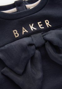 Marineblauer Sweatshirt mit "BAKER" in metallischem Schriftzug. Mit einer großen, strukturierten Schleife aus transparentem Material auf der Vorderseite. Weicher Stoff, gerippter Ausschnitt.