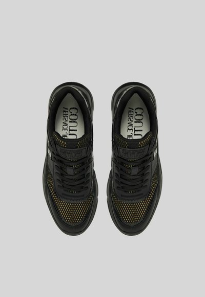 Sneakers neri con dettagli in rete, dotati di lacci neri e suola testurizzata nera. L'interno mostra il logo sulla soletta. Accenti metallici sui lati.