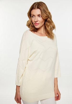 Hellbeige Strickpullover mit lockerer Passform. Mit einem Zickzackmuster und Dreiviertelärmel, abgeschlossen mit einem gerippten Saum.