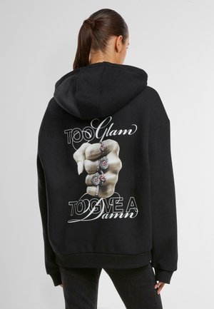 Black hoodie featuring a large graphic of a fist adorned with rings, with the text "TOO Glam TO GIVE A Damn" in white cursive on the back.