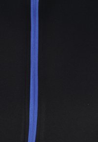 Tessuto nero con una cerniera blu centrale; texture liscia; design semplice; attenzione alla funzionalità senza ulteriori motivi o accenti.