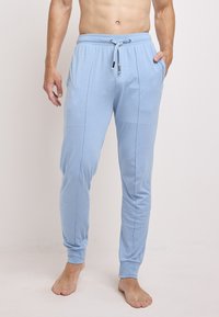 Lichtblauwe katoenen trainingsbroek met een trekkoord in de taille, zijzakken en een aansluitende boorden bij de enkels. Soepele textuur en slank design.