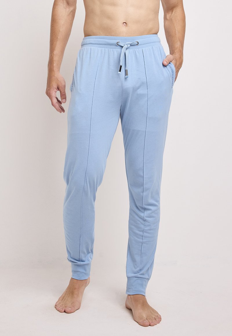 Lichtblauwe katoenen trainingsbroek met een trekkoord in de taille, zijzakken en een aansluitende boorden bij de enkels. Soepele textuur en slank design.