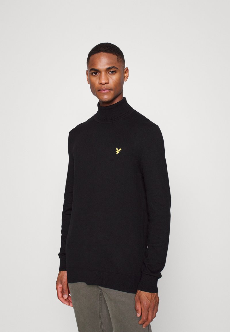 Maglione nero a collo alto realizzato in tessuto morbido, con un piccolo logo giallo sul petto. Maniche lunghe e polsini a coste.