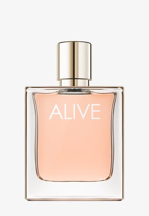 Clear rectangular perfume bottle with peach-colored liquid, gold cap, and the word "ALIVE" on the front.