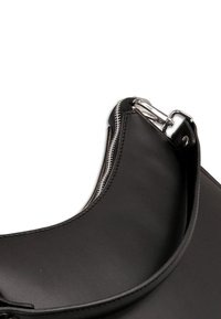 Sac à bandoulière en cuir noir avec un design incurvé, équipé d'une fermeture éclair argentée et de ferrures de sangle. Texture lisse, détails de couture précis.