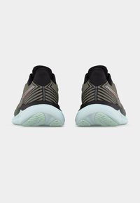 Ζευγάρι αθλητικών παπουτσιών σε ελιάς πράσινο και μαύρο με λευκές σόλες, εμφανιζόμενα από πίσω σε απλό ανοιχτό φόντο.