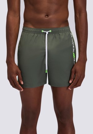Torace maschile e parte superiore delle gambe che indossano pantaloncini da bagno verde oliva con coulisse bianca e dettaglio del logo laterale in verde e bianco.