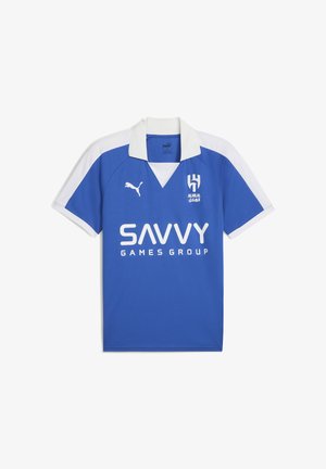 Camiseta de fútbol azul con mangas blancas, con cuello. Muestra los logotipos "AL HILAL" y "SAVVY GAMES GROUP" en blanco. Hecha de un tejido transpirable.