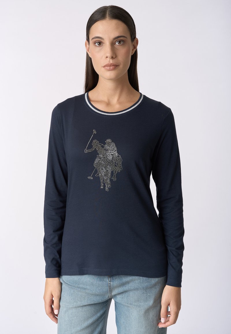 Maglietta a maniche lunghe blu navy con scollatura rotonda; presenta un design di un giocatore di polo in tonalità argento impreziosito con strass. Tessuto in cotone morbido.