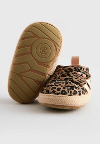 Slip-on-skor med leopardmönster, en texturerad tygovandel, elastiska remmar och en tan-färgad mönstrad sula. Har en dragflik på hälen.