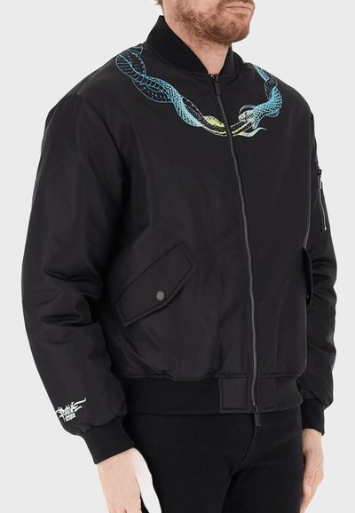 Giacca bomber nera con zip frontale, polsini e colletto a coste. Presenta un design colorato di serpente sulle spalle e tasche laterali.