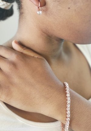 Roségoldschmuck mit einem Paar Ohrringe mit quadratischen Kristallen und einem passenden Armband, das mit funkelnden Steinen verziert ist.