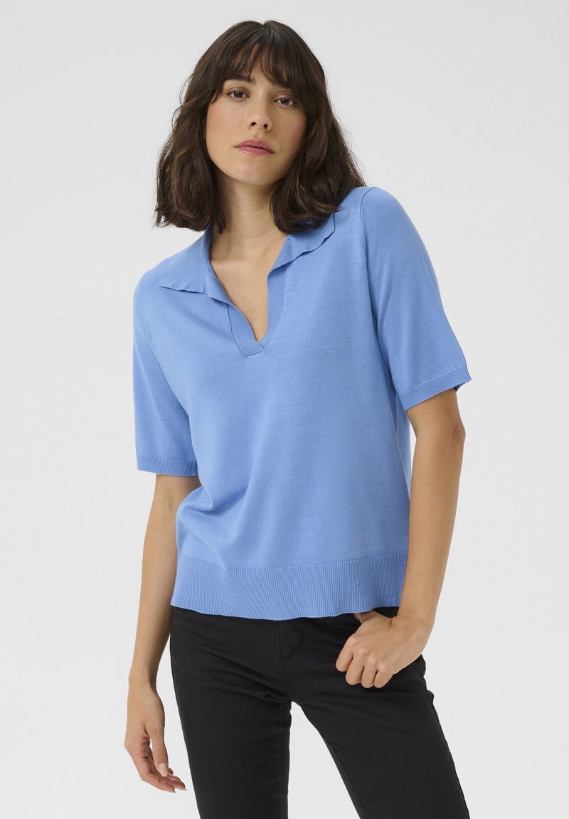 Light blue knitted polo-style sweater with a V-neck and short sleeves, featuring a ribbed hem and smooth texture.