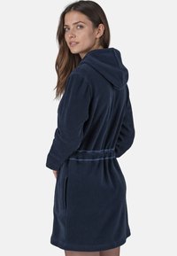 Mörkblå badrock med huva, tillverkad av mjuk fleece, med ett knytbälte, sidofickor och en strukturerad yta.