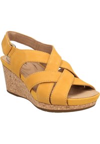 Sandalias de cuña de cuero amarillo con diseño de tiras cruzadas, punta abierta, tacón de corcho y tira de tobillo ajustable. Parte superior texturizada y plantilla acolchada.