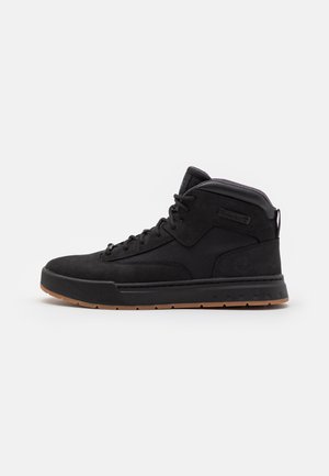 Baskets montantes Timberland noires avec semelle en caoutchouc marron, fermeture à lacets, col rembourré et logo de la marque sur le côté et la languette.