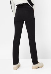 Sorte jeans i denim med slim fit, to baglommer og minimal syning. Kombineret med cremefarvede sko med en kraftig sål.