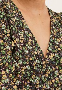 Abito a stampa floreale con profondo scollo a V, realizzato in un tessuto marrone scuro con fiori verdi, gialli e viola. Include maniche texturizzate.