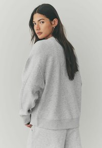 Grijze sweatshirt met een ontspannen pasvorm, lange mouwen, ribgebreide manchetten en zoom, en een zachte textuur, gecombineerd met bijpassende joggingbroek.