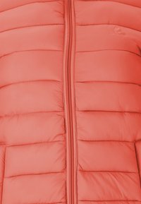 Vadderad jacka i ljus korall med en centrerad dragkedja, med horisontella quiltade paneler och slät syntetisk tyg.