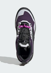 Lila und schwarze Sportschuhe mit Obermaterial aus Netzstoff, Schnürsystem mit Lockmechanismus, weißen Akzenten und strukturiertem Profil. Ortholite-Einlegesohle für Komfort.