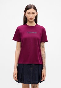 Burgunderfarget crew-neck t-skjorte i myk bomull, med broderte "Calvin Klein"-logo i kontrastfarge. Korte ermer, avslappet passform.