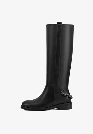 Stivale in pelle nera alto fino al ginocchio con un design elegante, suola piatta e una decorazione a catena argentata sul tallone. Trama liscia e cuciture minime.