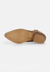 Suela de zapato de cuero marrón con una superficie lisa y un leve patrón de surcos; presenta un tacón apilado y un detalle de marca grabado. Talla 37.