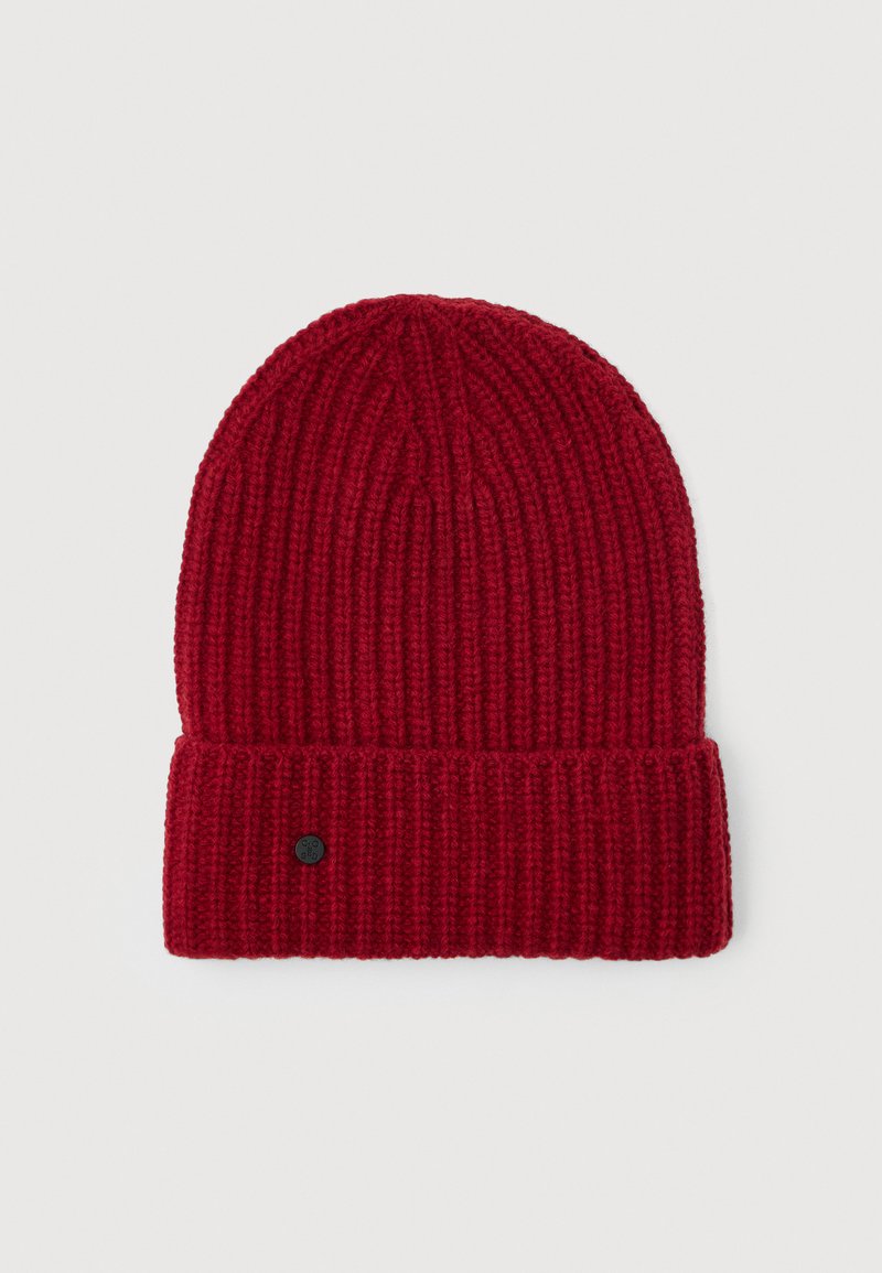 Red ribbed knit beanie with folded cuff and small round black logo tag on the cuff's left side, displayed on a white background.
