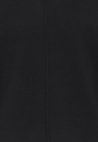 Pull noir avec une texture lisse, présentant une couture centrale verticale. Le matériau semble doux et tricoté sans motifs ni accents.