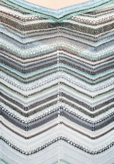 Πλεκτό τοπ με ριγέ σχέδιο σχήματος ζιγκ-ζαγκ σε ανοιχτό μπλε, μαύρο και ασημί, με υφή και λεπτομέρεια ανοιχτής ραφής, δημιουργώντας ένα εφέ πολλαπλών επιπέδων.