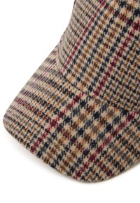 Gorra de cuadros marrón hecha de un tejido texturizado, con un visera curva y fibras contrastantes oscuras y claras en un patrón a cuadros.