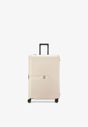 Valigia rigida beige con quattro ruote girevoli, scanalature verticali, manico telescopico nero e meccanismo di chiusura centrale.
